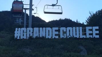 A sign with the text "#GRANDECOULEE" and a ski lift in the background.