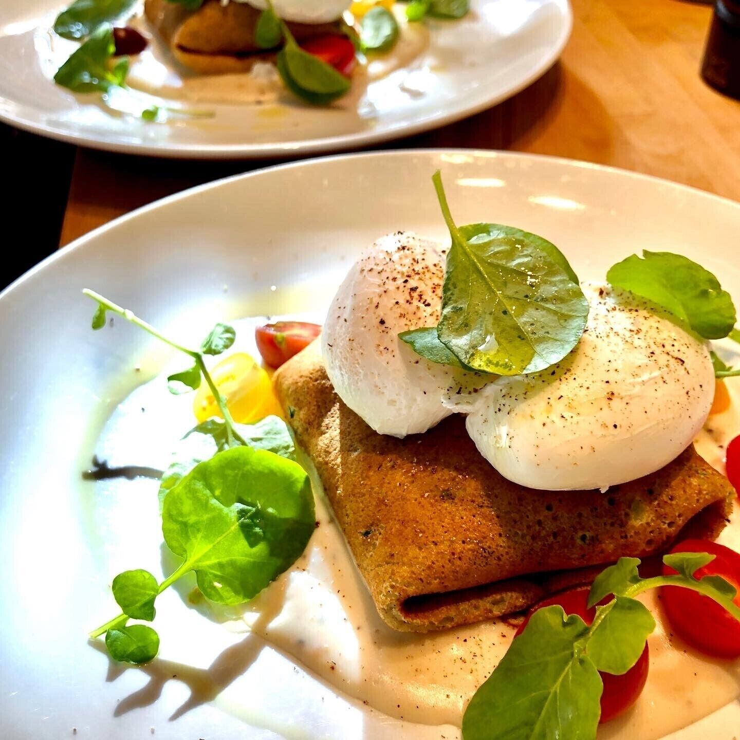 A plate with a poached egg on toast, garnished with a leaf and microgreens.