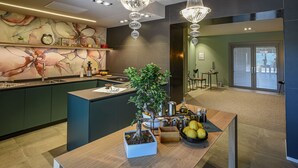 Een moderne keuken met een centraal kookeiland, een bonsai in een pot en een schaal met fruit.