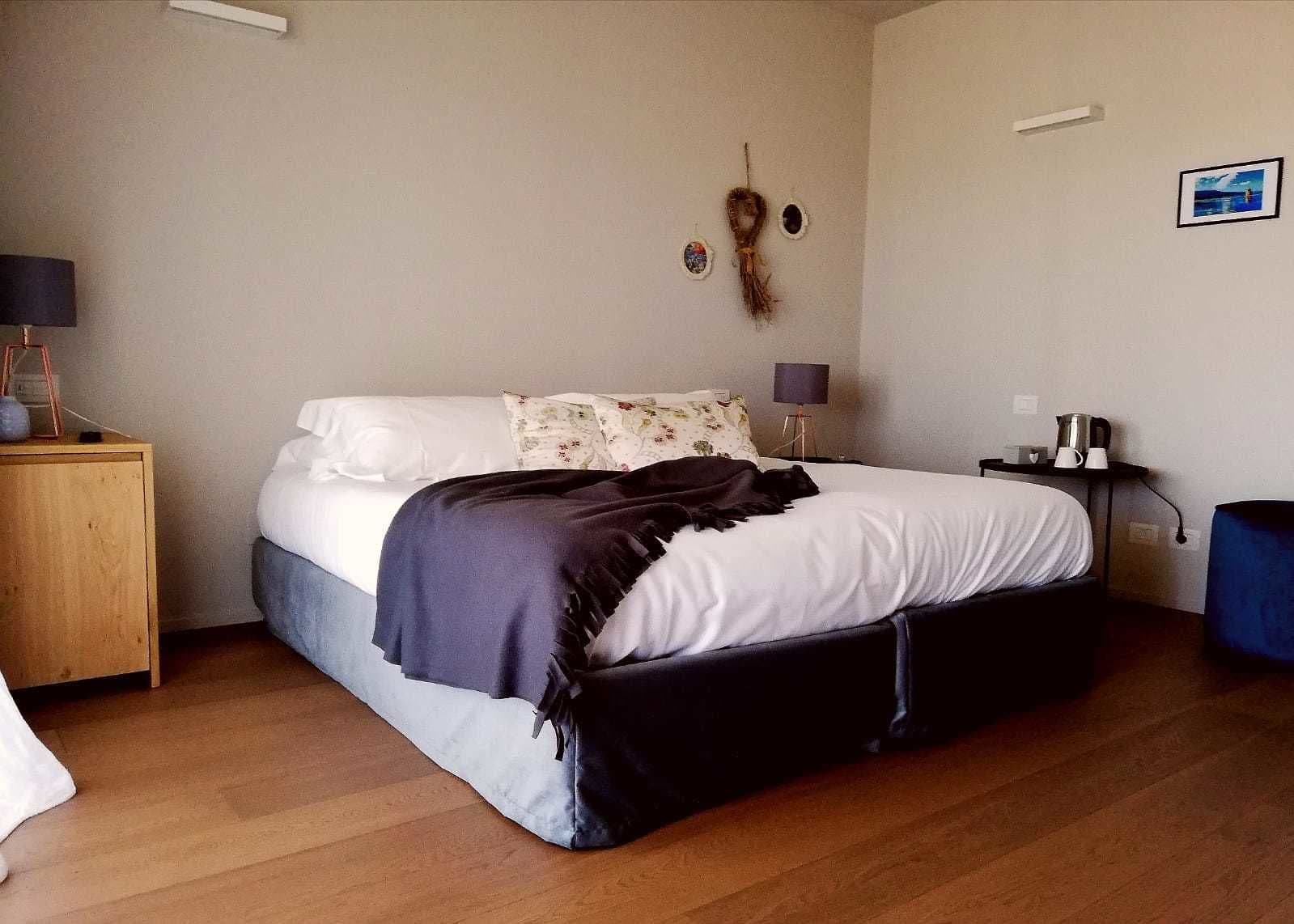 Un dormitorio con cama, mesitas de noche, una lámpara y un cuadro colgado en la pared.