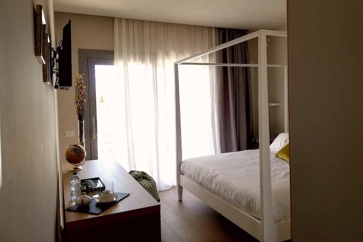 Une chambre à coucher avec un lit à baldaquin, un bureau avec une chaise et un téléviseur fixé au mur.