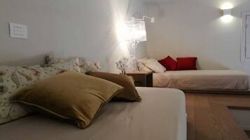 Une chambre à coucher avec un lit, deux oreillers, une table de chevet, une lampe et un luminaire fixé au mur.