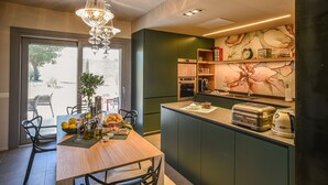 Een moderne keuken met een eethoek, met een houten tafel, stoelen, een kroonluchter en een groot raam.