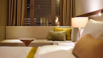 A hotel room with a sofa, a small round table, and a lamp.