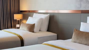 A hotel room with two beds, a lamp, and a curtain.