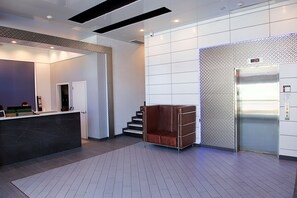 A modern lobby with a reception desk, a staircase, and an elevator. - 7 Days Hotel Bronx (Bronx)
