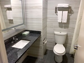 A bathroom with a marble wall, a sink with a soap dispenser, a toilet, and a towel rack. - 7 Days Hotel Bronx (Bronx)
