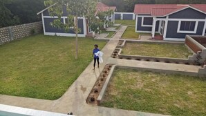 A residential area with a paved pathway, a lawn, and multiple houses with red roofs. - Vosteen Home Holidays (Watamu)