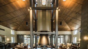 Un'ampia hall con divani in pelle, un tavolino centrale e un soffitto alto con travi a vista.