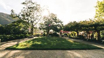 Un jardín bien cuidado con un camino de grava, bancos y árboles.