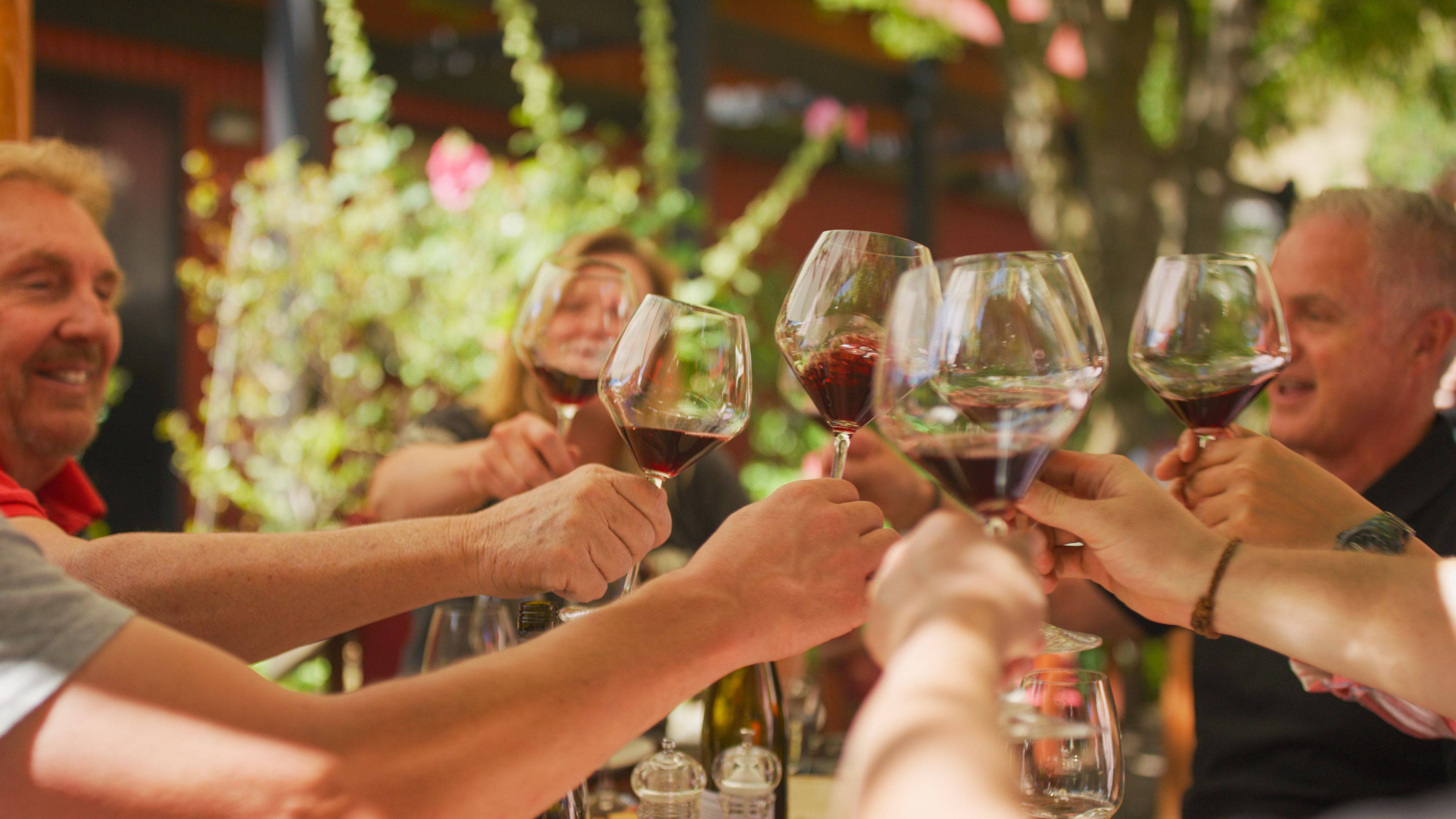 Um grupo de pessoas brindando com taças de vinho em uma mesa.