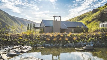 Situated in a lush valley, this single-story building features a pond and rolling hills.