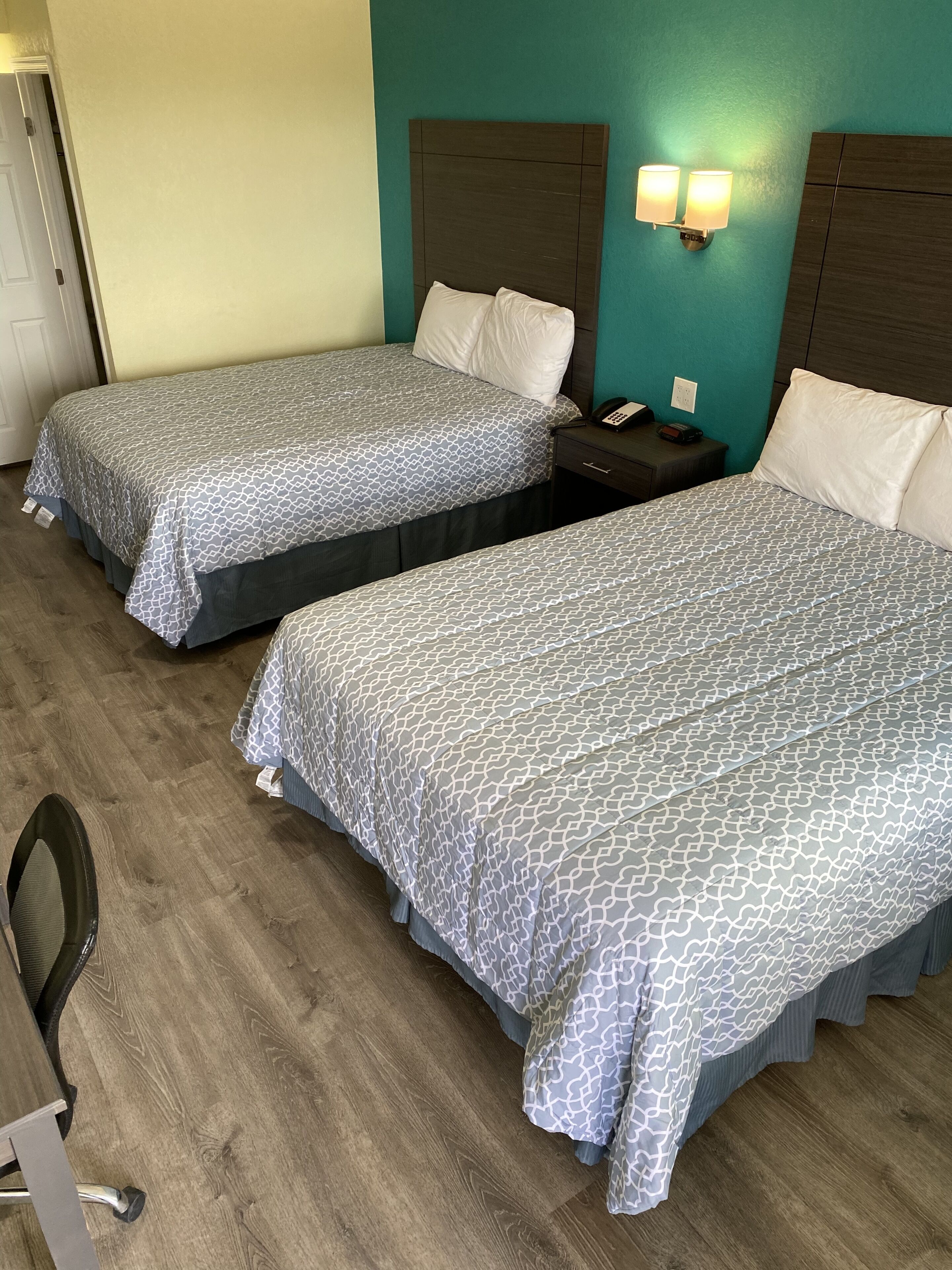 Two twin beds with matching headboards and footboards, a bedside table with a lamp, and a chair.