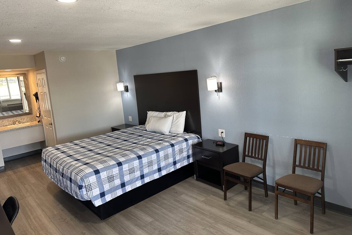A hotel room with a bed, two nightstands, a desk, and two chairs.