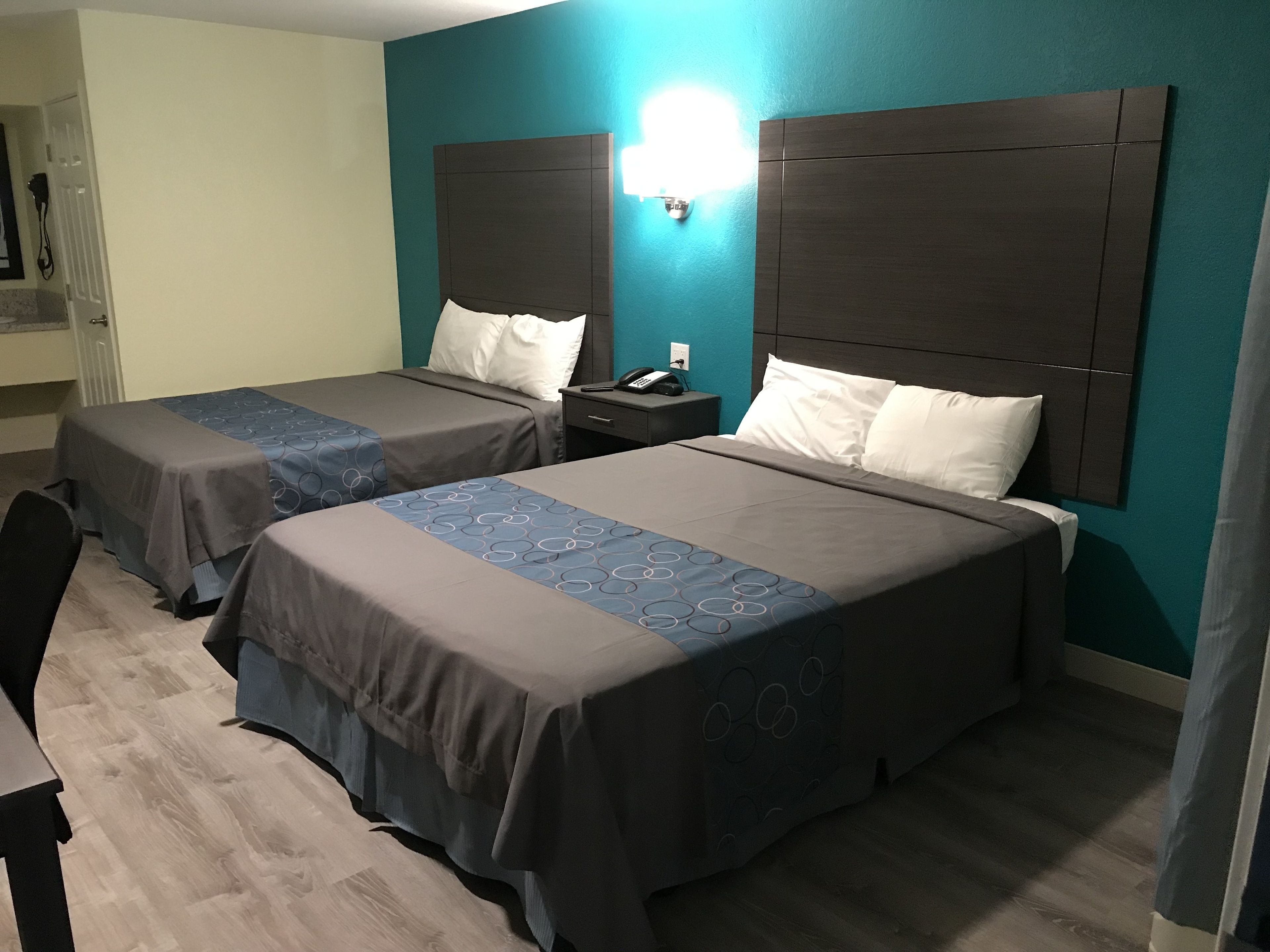 A hotel room with two beds, a desk, and a nightstand.