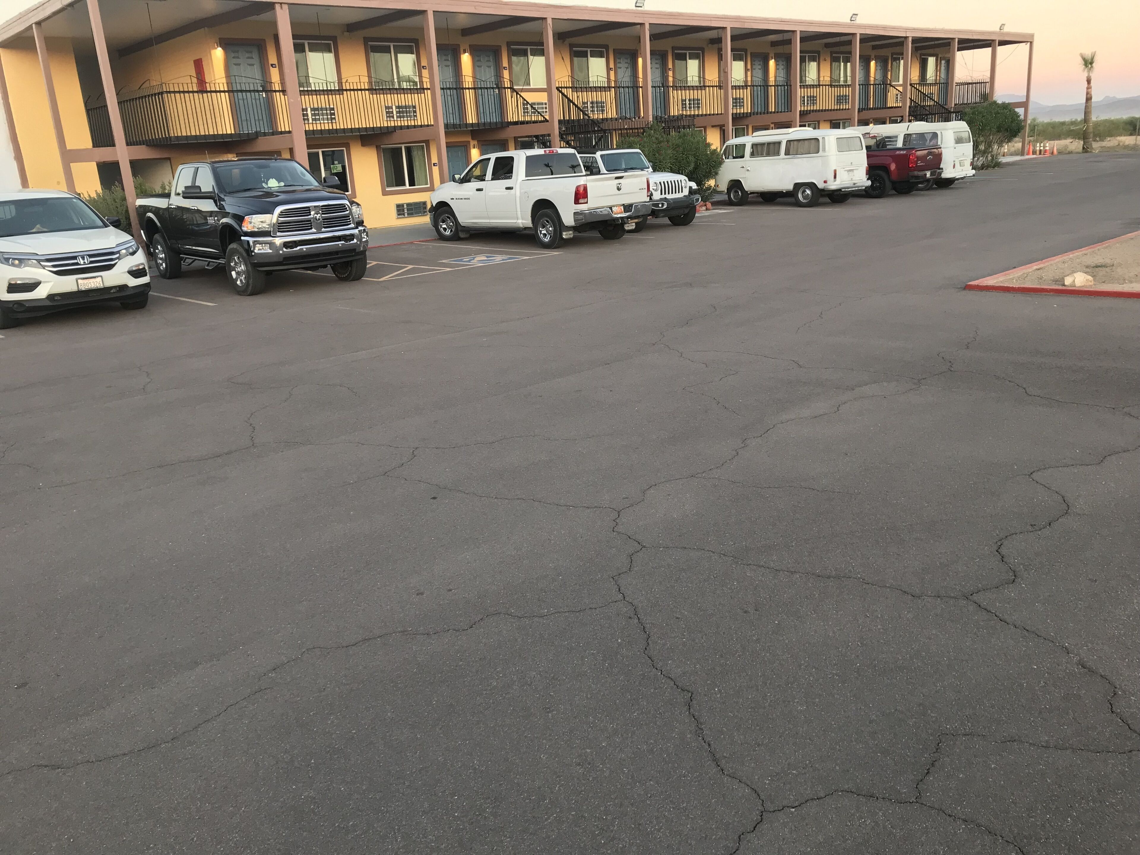 A parking lot with several vehicles, including a white pickup truck, a black truck, and a white van.