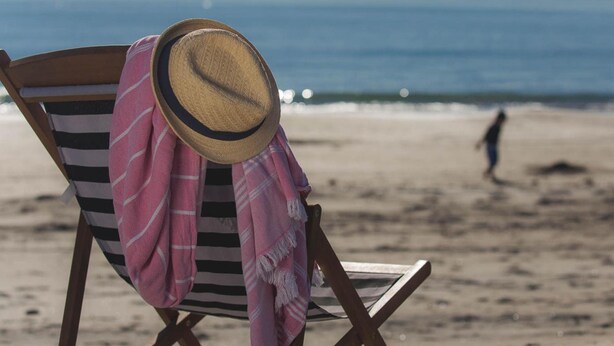 A beach chair with a straw hat and a pink and white striped towel. - Pacific Park Christian Holiday Camp (Tauranga)