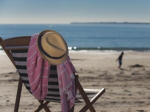 A beach chair with a straw hat and a pink and white striped towel. - Pacific Park Christian Holiday Camp (Tauranga)