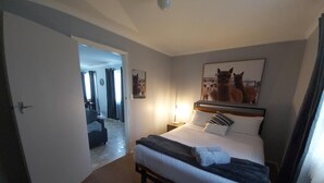 A hotel room with a bed, a nightstand, a lamp, and a painting of a dog. - Kalgan River Chalets and Caravan Park (Kalgan)