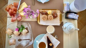 A breakfast setting with various food items, a teapot, and a cup of tea. - Il Tramonto (Giba)