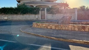 A house with a stone wall and a large rock in the driveway. - Il Tramonto (Giba)
