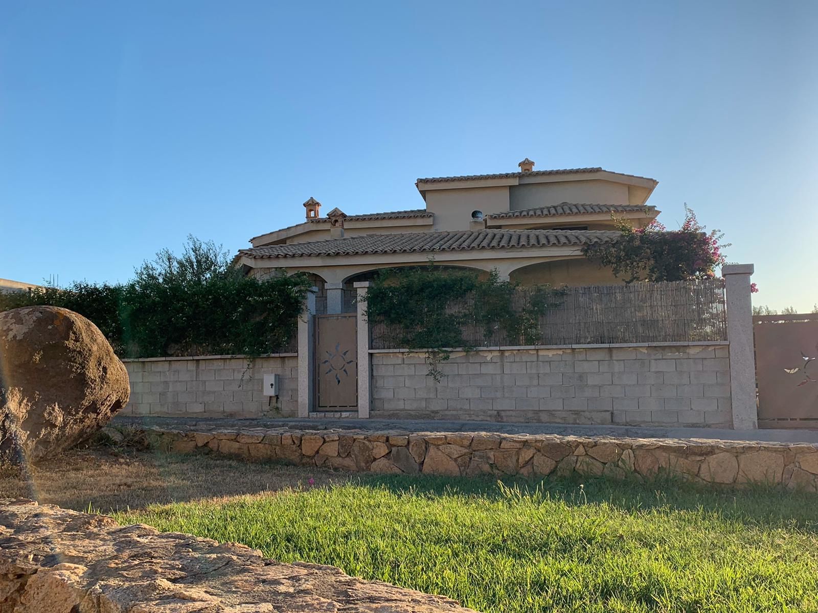 A traditional building with a tiled roof, a stone wall, and a gate.