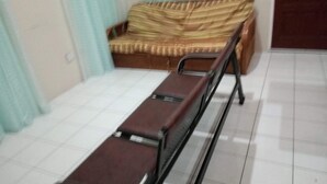 A hospital bed in a room with a tiled floor and a sofa with a striped cushion. - Digs Cottages (Portsmouth)