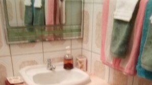 A bathroom with a wooden cabinet, a sink, and a mirror. - Digs Cottages (Portsmouth)