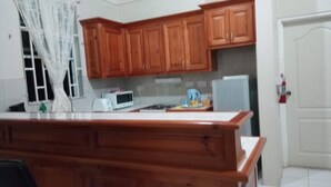 A kitchen with wooden cabinets, a microwave, and a refrigerator. - Digs Cottages (Portsmouth)