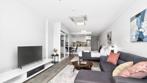 A modern living room with a flat-screen TV, a sofa, a coffee table, and a rug. - 188 Apartments (Perth)