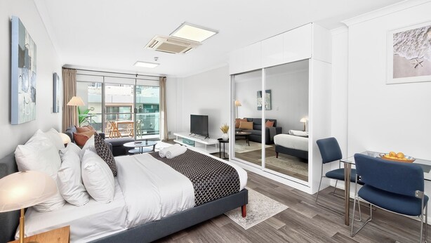 A modern hotel room with a bed, a desk, a chair, and a balcony with a view. - 188 Apartments (Perth)