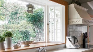 A kitchen with a large window, a sink, and cabinets. - Goodin Country Garden (Warea)