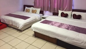 A hotel room with two beds, each with a white and purple bedspread, and a red chair.