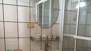 A bathroom with a toilet, sink, and a glass shower enclosure.