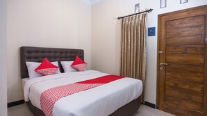 A neatly made bed with a red and white patterned bedspread, two pillows, and a wooden headboard. - Hotel O Al Abror Homestay (Yogyakarta)