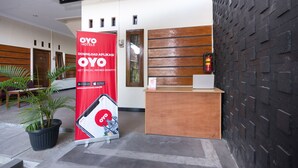 A reception area with a wooden reception desk, a black brick wall, and a red banner advertising OYO Hotels. - Hotel O Al Abror Homestay (Yogyakarta)