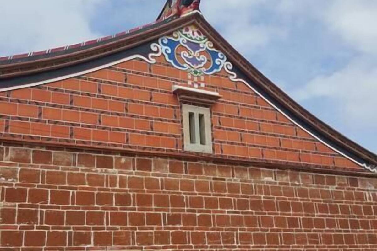 Un bâtiment en briques, doté d’un toit décoratif et d’une petite fenêtre.