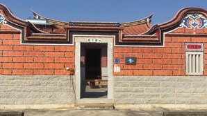 A traditional building with a brick facade, a wooden door, and a small sign above the door. - Rong Shu Xia B&B (Jinning)