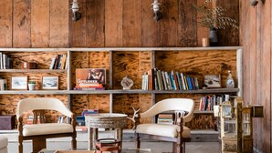 A room with wooden walls, a glass coffee table, leather ottoman, and two chairs. - Cuyama Buckhorn (New Cuyama)