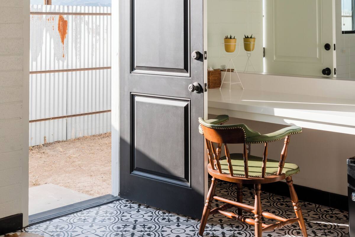 A modern bathroom with a large mirror, a wooden chair, and a patterned floor.