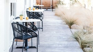 A row of tables and chairs outside a building, with a pathway and plants along the side. - Cuyama Buckhorn (New Cuyama)