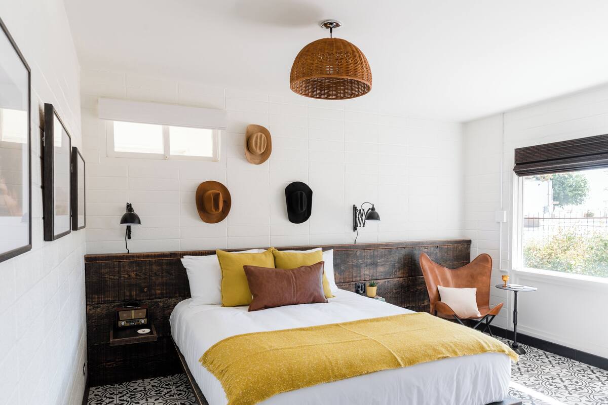 A neatly arranged bedroom with a bed, bedside tables, a small table, and a window.