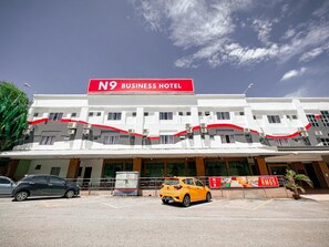 Un edificio de dos pisos con un llamativo letrero rojo que dice 'N9 BUSINESS HOTEL' en la parte superior.