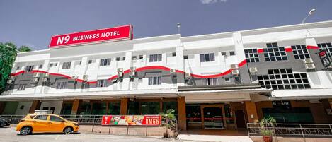 Un edificio de varios pisos con un llamativo letrero rojo que indica que es un hotel para negocios.