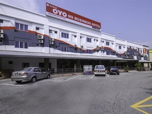 Un hotel de negocios con cartel, varios espacios de estacionamiento y una zona cubierta para aparcar.