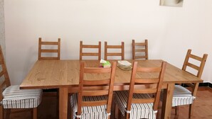 A wooden dining table with six chairs, each with striped cushions. Above the table, there are three framed pictures on the wall. - 37 Garden Guesthouse Shilin Family (Kunming)