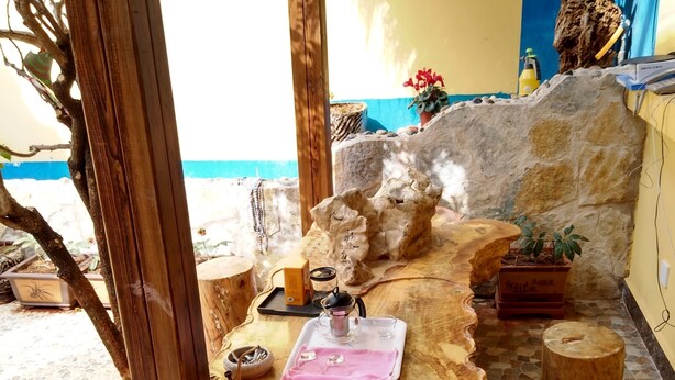 A wooden table with a glass top, surrounded by stone tiles and wooden stools. - 37 Garden Guesthouse Shilin Family (Kunming)