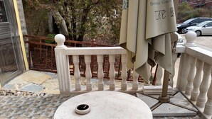 A small outdoor seating area with a round table and a white chair, a tiled floor, and a metal fence in the background. - 37 Garden Guesthouse Shilin Family (Kunming)