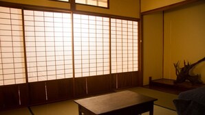 A traditional Japanese room with tatami flooring, a low wooden table, and a shoji screen. - Engawa (Tonosho)