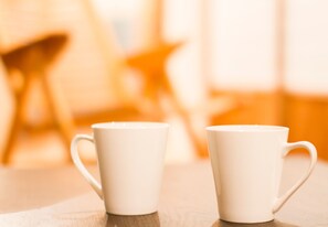Two white ceramic mugs on a wooden table with a blurred background suggesting a cozy indoor setting. - Engawa (Tonosho)